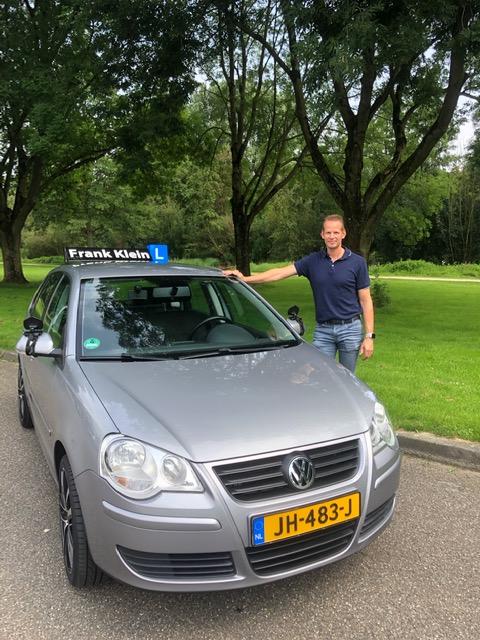 Frank Klein naast de Volkswagen lesauto met het Frank Klein L-bord en kenteken JH-483-J